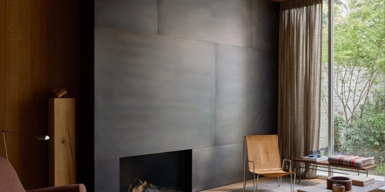 La chimenea con paneles de acero forma el corazón de una casa renovada de los años 50
